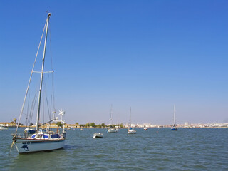 Small boats anchored on Seixal Bay with a view of the city of Barreiro on the horizon. Seixal,...