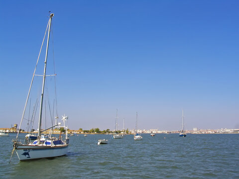 Small boats anchored on Seixal Bay with a view of the city of Barreiro on the horizon. Seixal, Setubal, Portugal
