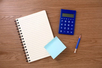 Calculator and notebook on wooden texture background. Flat lay of a workplace. Accounting workplace concept. Top view over head.