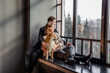Couple guy and girl with red shiba inu dog on window sill