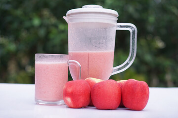 Pink apple fruits smoothie in glass and blender, outdoor background.Concept, healthy beverage for...