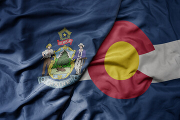 big waving colorful national flag of colorado state and flag of maine state .
