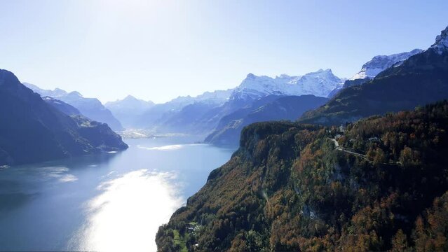 panoramic aerial view of Lake  Uri below the alpine village of Seelisberg featuring the Swiss town of  Fl&uuml;elen and Brunnistock mountain with snow-capped peaks in Switzerland 
