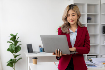 Young Asian woman working using laptop computer and financial documents in her workplace, freelancer, online marketing, telemarketing concept, e-commerce