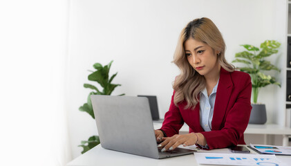 Young Asian woman working using laptop computer and financial documents in her workplace, freelancer, online marketing, telemarketing concept, e-commerce