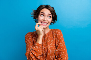 Photo of funny curious lady bite nail finger look side stressed made mistake isolated over blue color background - obrazy, fototapety, plakaty
