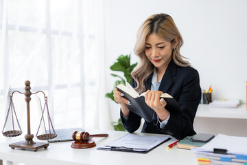 Attractive young Asian lawyer working in the office with contract and legal documents when sitting...