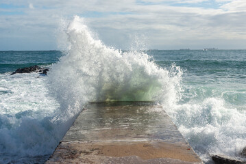 Sea wave crashing hard on a beach pier. Wild nature. Seasons