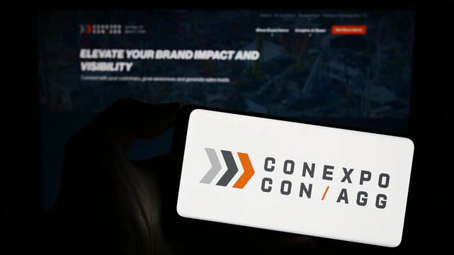 Stuttgart, Germany - 11-09-2023: Person holding mobile phone with logo of American construction trade show CONEXPO-CON-AGG in front of web page. Focus on phone display.