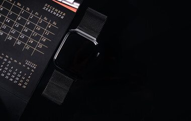 Task planning. Calendar and smart watch on a black background. Stock photo on the topic of schedules