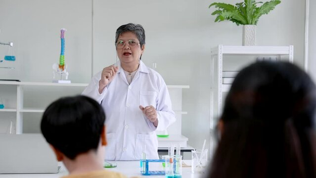 Close-up teacher standing in front class teaching students in science classroom, teacher's face always has happy smile while teaching, make every student happy involved in learning.