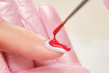 Woman applying nail polish. Close up process of applying red varnish.  Woman in salon receiving...