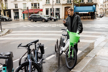 Micromobility ecology. Green sustainable mobility Young man unlocks an e-scooter with his mobile...