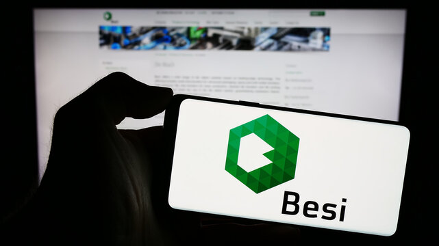 Stuttgart, Germany - 11-11-2023: Person holding cellphone with logo of Dutch company BE Semiconductor Industries NV (Besi) in front of business webpage. Focus on phone display.