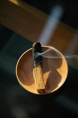 Burning and smoking palo santo on a wooden plate