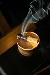 Burning and smoking palo santo on a wooden plate