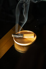 Burning and smoking palo santo on a wooden plate