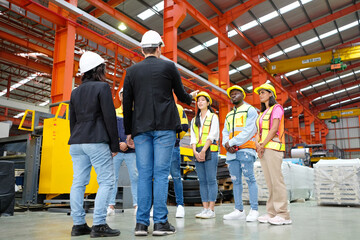 Engineers and employees stand in a meeting to plan work in an industrial factory.