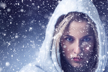 portrait of a girl in a hood. A blonde woman in a hood looks at the camera, her face is snowing in a close-up. winter portrait concept