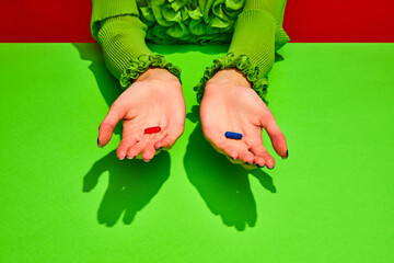 Unrecognizable woman holds two pills, red and blue tablets. Vitamins of beauty and health against sickness and ugliness. Choice true or false. Concept of medicine, viruses, immune system, healthcare. - obrazy, fototapety, plakaty