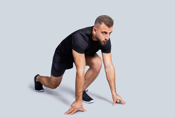 Obraz premium Strong focused young caucasian guy athlete in sportswear, stay on start, ready to run