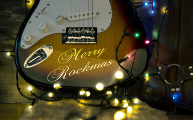 Old used vintage guitar with Christmas lights on a wooden plank