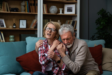 Senior couple elderly man, husband taking care comforting her sick wife massage her and hugging because she have pain and headache years after car crash accident. Woman with meteoropathy feeling sick