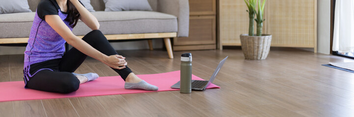 Fototapeta na wymiar Beautiful healthy woman practicing yoga, Stretch or warm up before exercising, Calming the mind and meditating in her living room, Dumbbells and a protein shake or bottle of water, Healthy exercise.