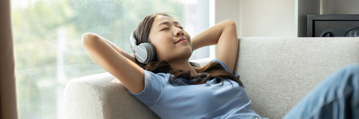 Woman happily listening to music on her favorite sofa in the living room, Relaxation time, Happy...