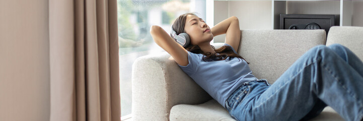 Woman happily listening to music on her favorite sofa in the living room, Relaxation time, Happy time, Feel good, Happy women resting at work after work is finished, Chill, Fatigue is eased. - obrazy, fototapety, plakaty