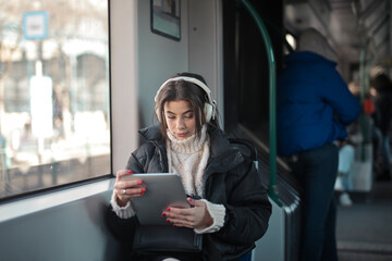 young woman listens to music on the train from a tablet.?