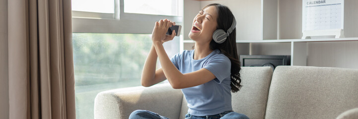 Young Asian woman happily listening to music through headphones, Woman was enjoying listening to...