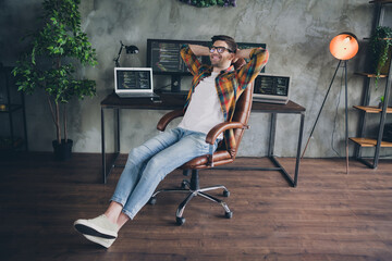 Full size photo of satisfied positive front end developer sit chair hands behind head accomplish tasks workstation modern office indoors