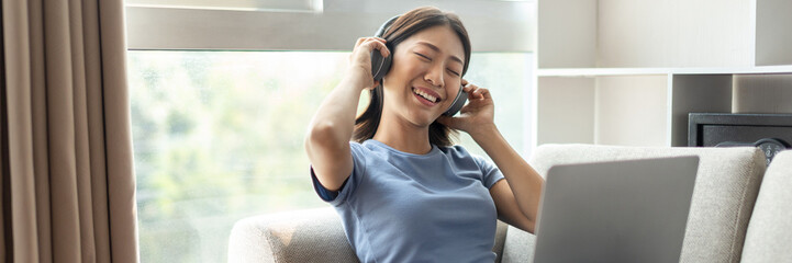 Young Asian woman happily listening to music through headphones, Woman was enjoying listening to her favorite music and rocking to the beat of the music, Stress relief, Happiness in life.