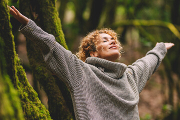 Overjoyed happy woman enjoying the green beautiful nature woods forest around her - concept of female people and healthy natural lifestyle - happiness emotion and adult lady opening arms with joy - obrazy, fototapety, plakaty