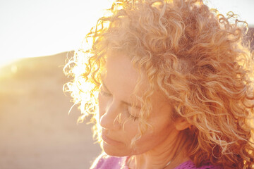 Portrait of young adult woman with closed eyes enjoying the sunlight in sunset outdoor. Life...