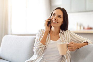 Pleasant Call. Happy Woman Talking On Phone And Drinking Coffee At Home