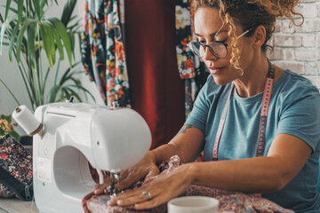 One worker woman at home or workshop using and working with sewing machine as a seamstress. Happy worker female people with home alternative business lifestyle concept. Designer making clothes hobby - obrazy, fototapety, plakaty