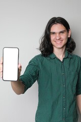 Young handsome guy with long hair showing the screen of his phone