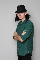 Young handsome man emotional pose with hat. Portrait of handsome young serious confident young guy with long hair in hat.