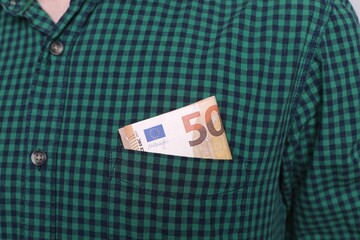 Cash into the pocket of shirt. Money 50 euros in the pocket of green checkered shirt. Earning and saving money