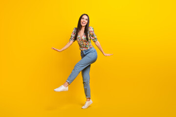 Fototapeta na wymiar Full size photo of adorable positive woman wear stylish top denim pants dancing jumping have fun isolated on yellow color background