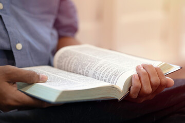 A close-up of a hand male opening and reading a book.