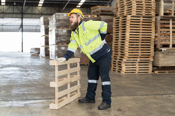 Male warehouse worker feeling backache after carrying wood pallet at wood warehouse