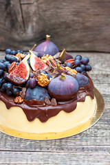 Delicious vanilla cheesecake poured with melted dark chocolate, figs, grape, pecan nuts on the top. Harvest autumn decoration