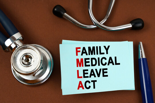 On a brown surface there is a stethoscope, a pen and blue stickers with the inscription - family medical leave act