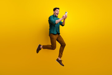 Fototapeta na wymiar Photo of cheerful positive excited man dressed trendy outfit reading instagram telegram twitter post isolated on yellow color background