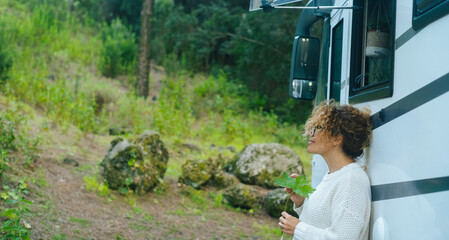 One serene woman enjoy relax and calm outdoors standing outside a camper van and admiring green...