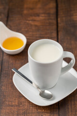 Fototapeta na wymiar Milk in a porcelain cup and honey in a porcelain bowl on a wooden table