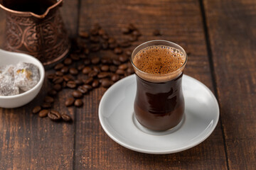 Turkish coffee in glass tea cup with Turkish delight on wooden table